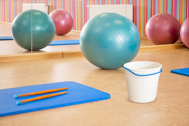 Collection of inflatable exercise balls next to a bucket and a pair of drum sticks