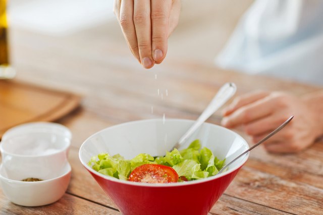 Person seasoning a salad