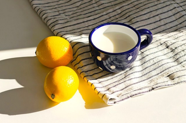 Two lemons next to a mug on a placemat