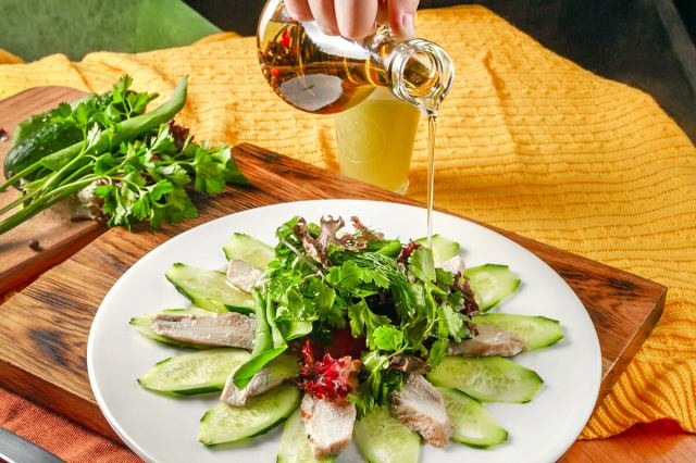 Person pouring oil over a salad