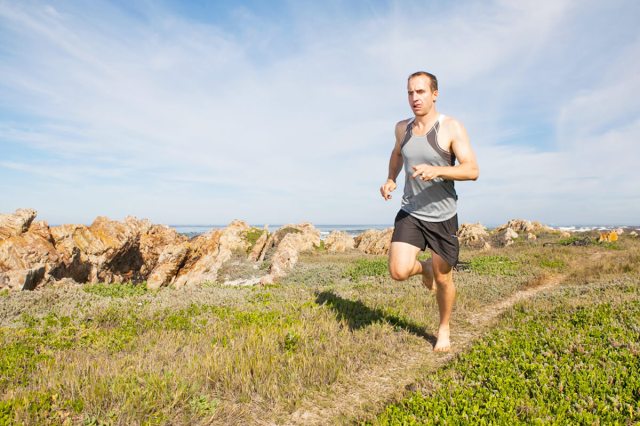 Man running barefoot on a trail