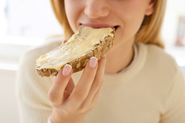 Woman eating a slice of bread with butter on it