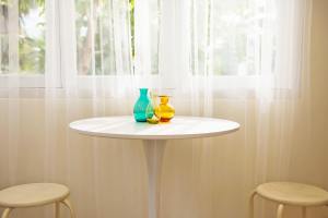 Brightly lit room with a table by the window with three vases on it