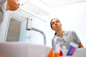 Woman swishing mouthwash above a sink