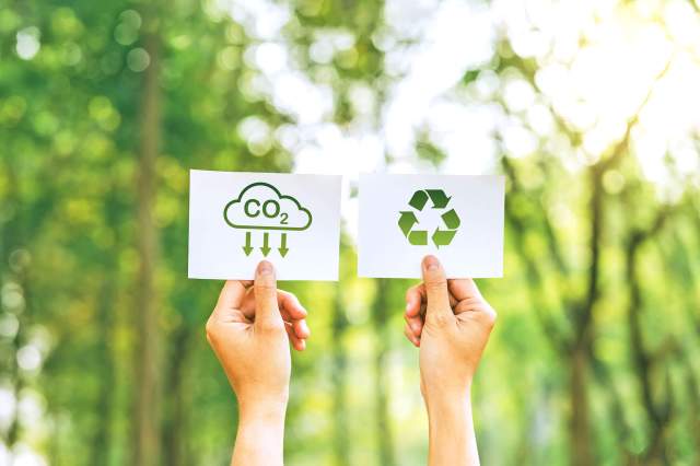 Person holding up two sign promoting recycling and taking care of the environment