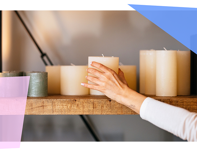 A person adding a white candle to a collection of white candles 