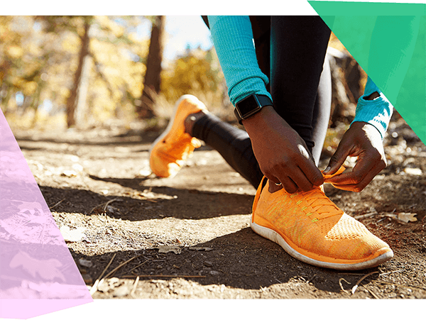 Person tying laces of orange running shoes on a trail 