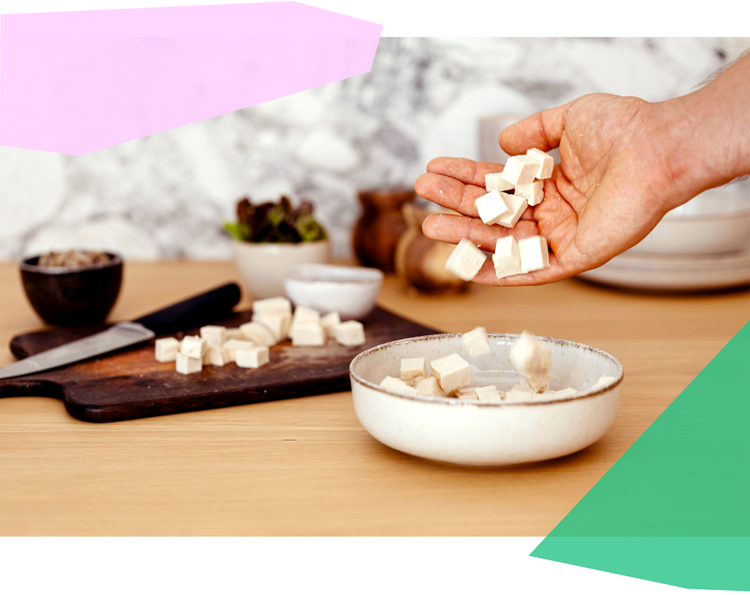 Person putting chopped tofu into a bowl 