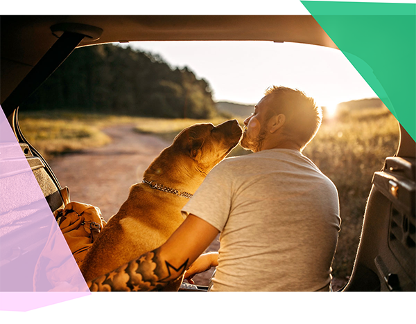 Man sitting in the back of his car with his dog 