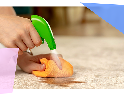 Person spraying a cleaner and rubbing down a surface with a towel 