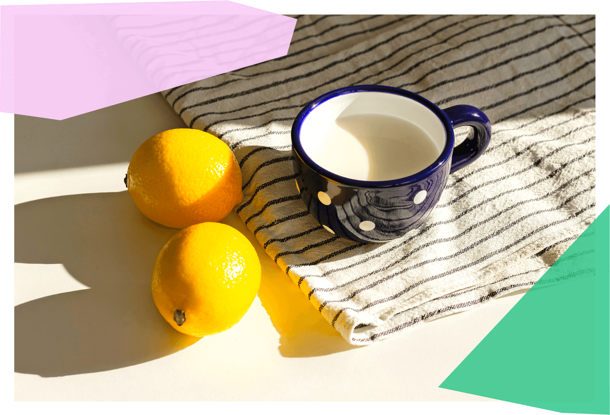 Two lemons next to a mug on a placemat 