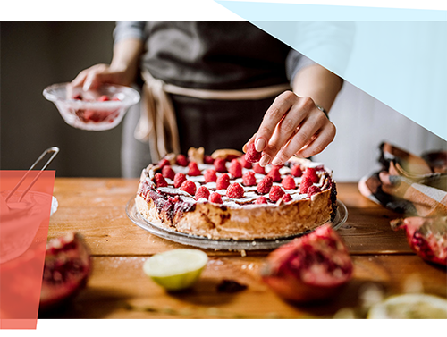 Person putting berries on top of a cake 