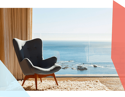 A luxury chair and rug near an ocean-front balcony view 