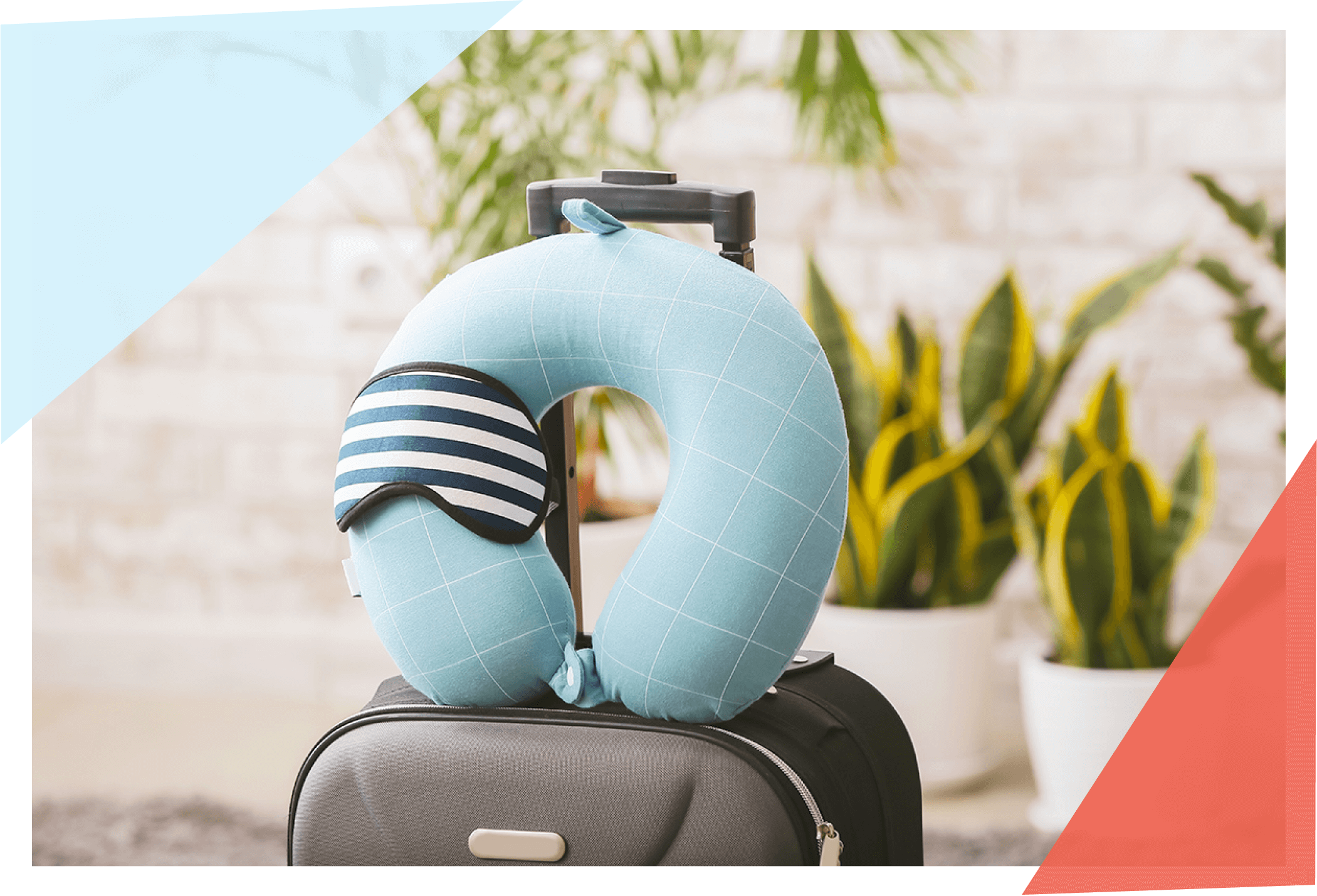 Travel pillow and eye mask on top of a suitcase 