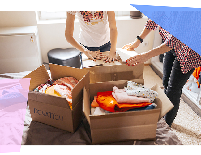 Two people sorting clothes into donation boxes 