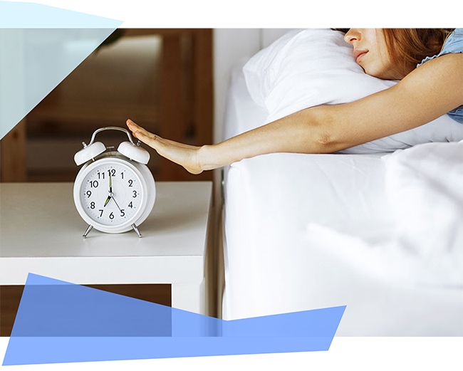 Person in bed hitting their alarm clock 