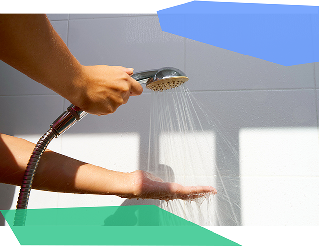 Person holding a shower head above their hand and running it. 