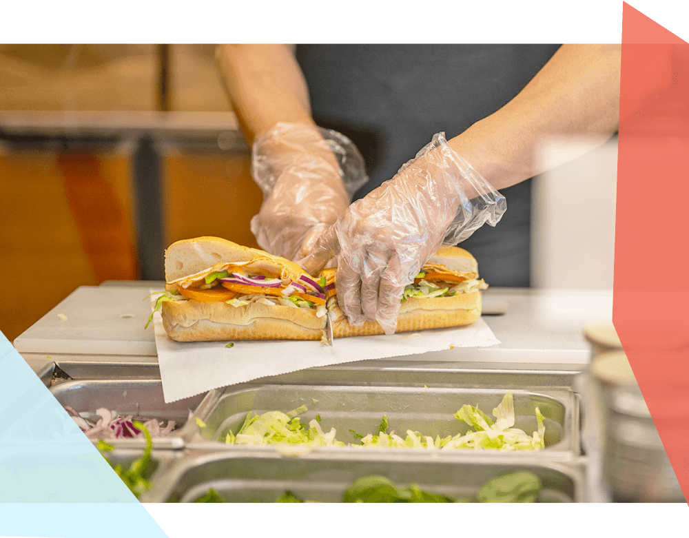 Fast food worker cutting a sub in half. 