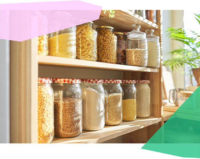 Dry grains and pasta in glass jars on shelves. 