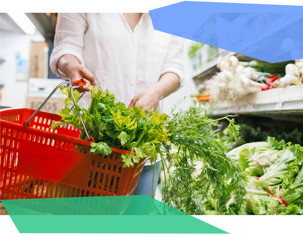 Person holding a shopping basket filled with produce. 
