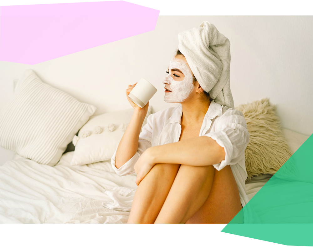Beautiful woman wearing a facial mask and drinking tea in bed 