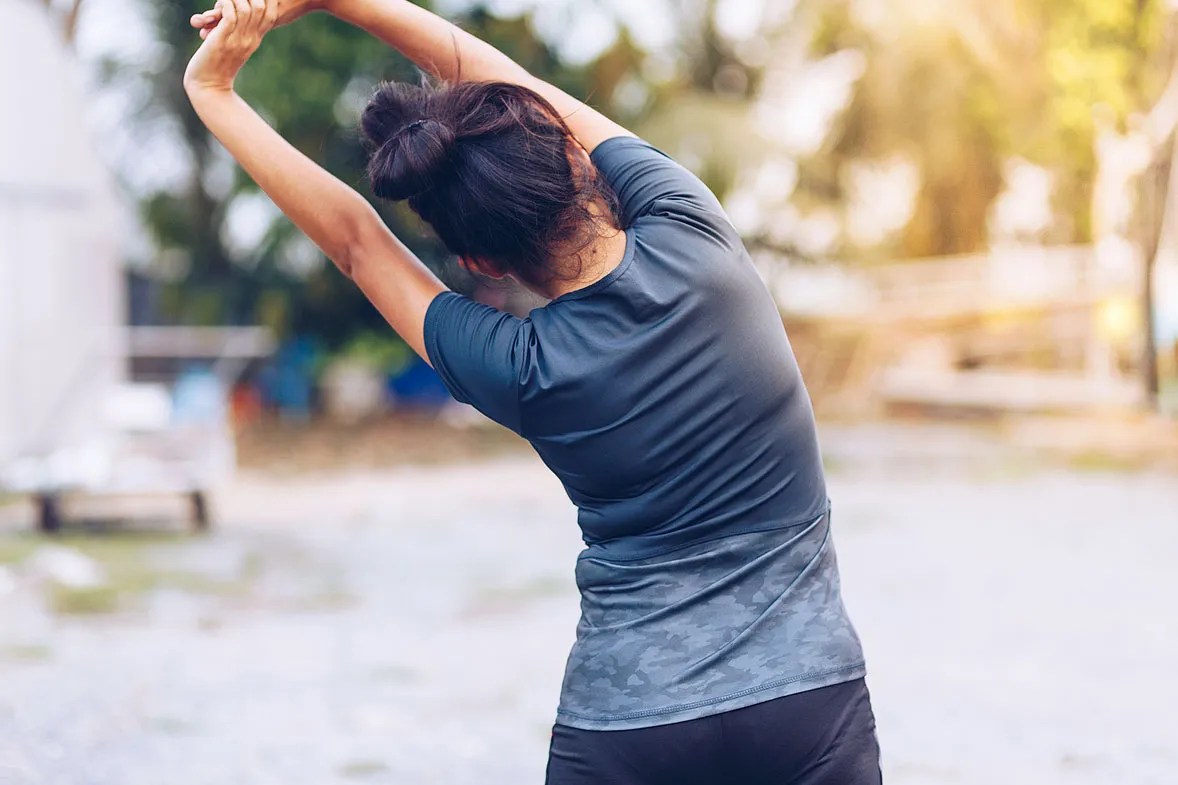 Woman stretching both hands over her head. 