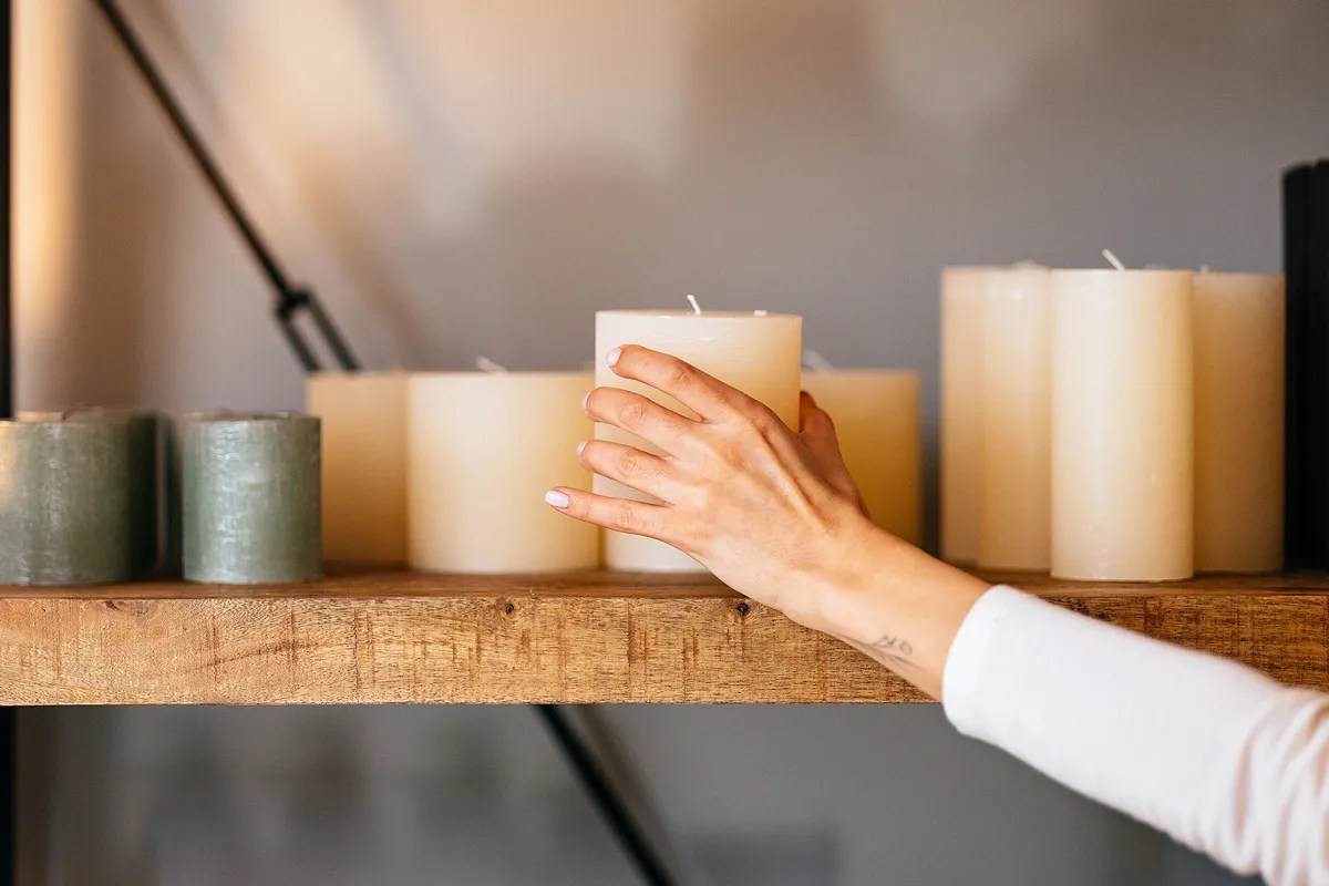 A person adding a white candle to a collection of white candles
