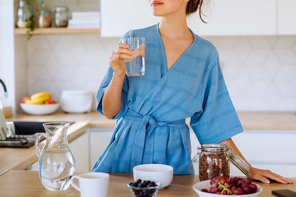 Woman standing out counter drinking water 
