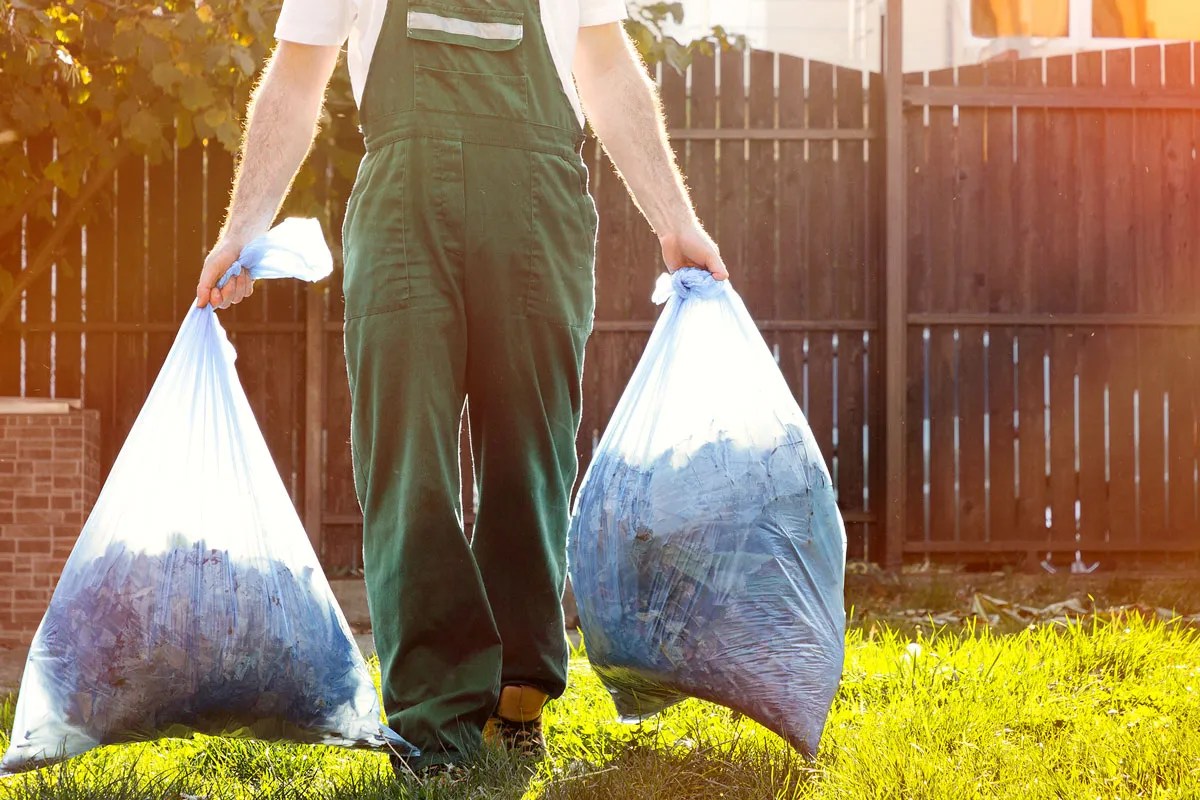Person carrying a garbage bag in each hand