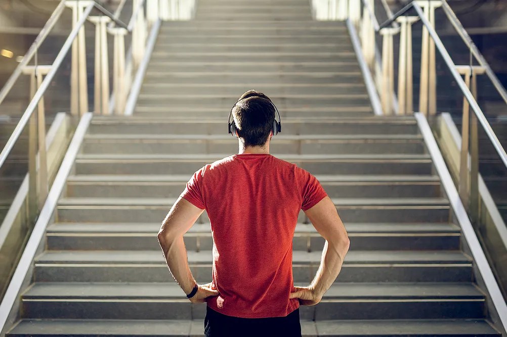 Man wearing workout gear and headphones at the bottom of a flight of steps