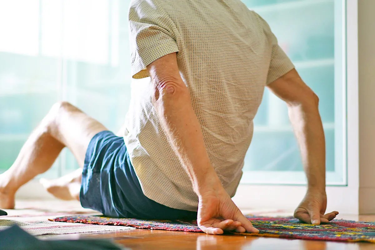 Man sitting on rug with his arms behind him holding him up 