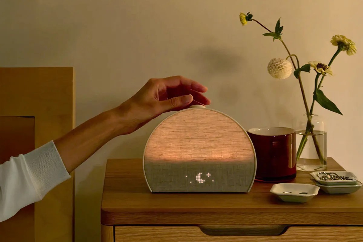 A person turning on/ off their bedside table alarm clock 