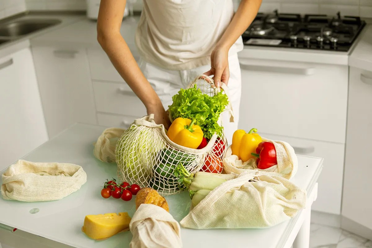 Woman unpacks reusable grocery bags full of vegetables