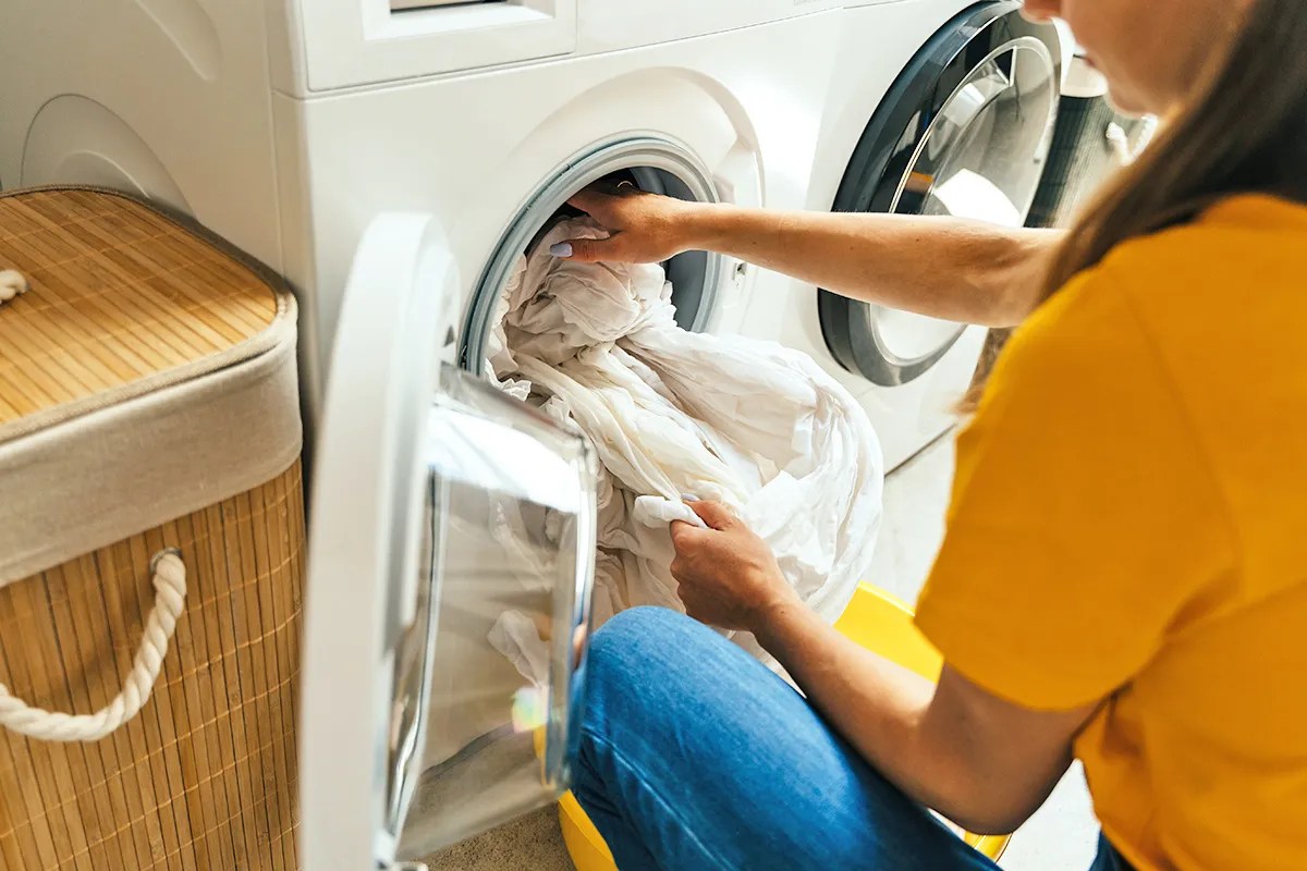 woman unloads the linens from the washing machine  