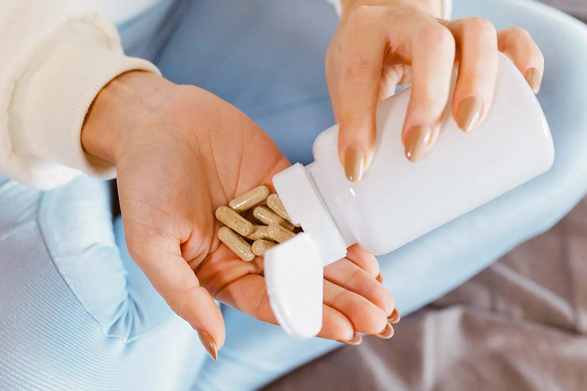 Close-up of woman pouring pills into her hand 