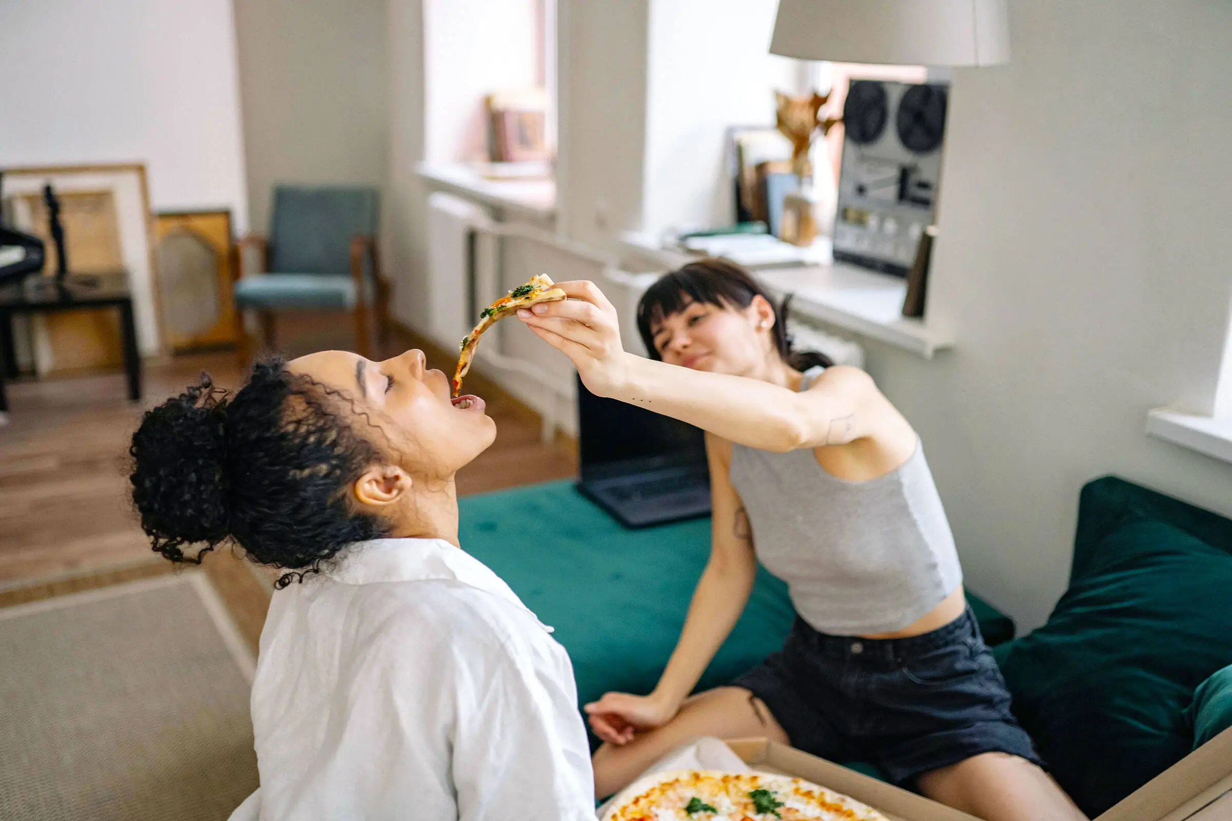One person feeding the other a slice of pizza. 