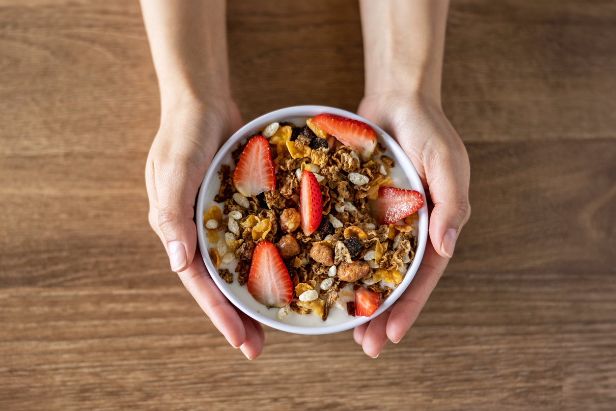 Person holding a bowl with granola and fruit in it. 