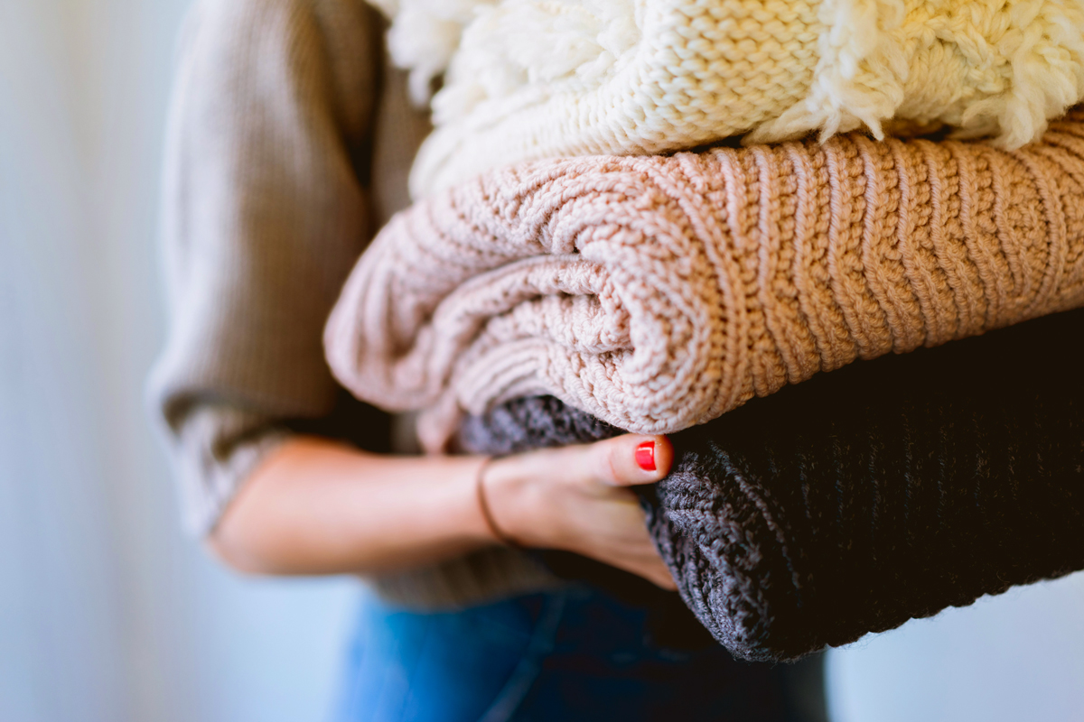 Person carrying pile of folded bulky laundry
